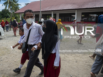 A father leads his two children to take the COVID-19 vaccine at Porame Public Elementary School, Porame Village, Sigi Regency, Central Sulaw...