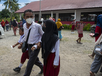 A father leads his two children to take the COVID-19 vaccine at Porame Public Elementary School, Porame Village, Sigi Regency, Central Sulaw...