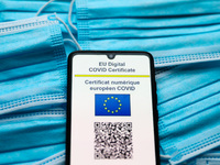 EU Digital COVID Certificate is displayed on a mobile phone screen photographed on surgical masks background for illustration photo during t...