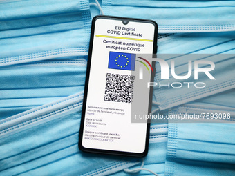EU Digital COVID Certificate is displayed on a mobile phone screen photographed on surgical masks background for illustration photo during t...