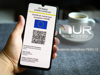 EU Digital COVID Certificate is displayed on a mobile phone screen photographed with a cup of coffee in the background for illustration phot...