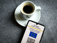EU Digital COVID Certificate is displayed on a mobile phone screen photographed with a cup of coffee in the background for illustration phot...