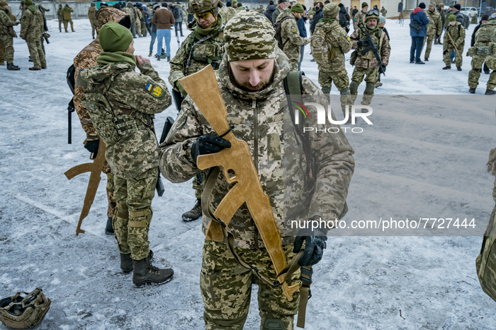 Volunteer of the 112th Territorial Defense Brigade of Kiev prepares his wooden training rifle during a military exercise for civilians in th...