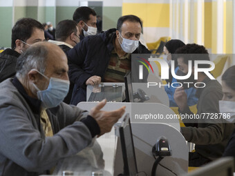 Health personnel (R) check documents of Iranian people who are waiting to receive a dose of the new coronavirus disease (COVID-19) vaccine d...