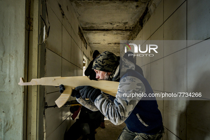 A civilian volunteer for the Territorial Defense Brigade of Kiev, performs a military exercise inside a building with a wooden training rifl...
