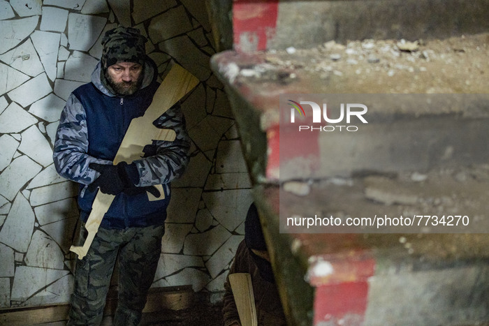 A civilian olunteer for the Territorial Defense Brigade of Kiev, holds a wooden training rifle during a military exercise inside a building....