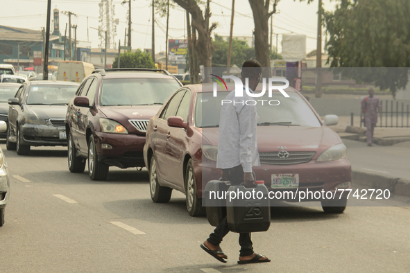 A man crossing the road with two jerrycan filled with petrol from a filling station in Lagos, 08 February 2022. Fuel scarcity has hit Lagos...