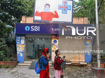 A COVID-19 awareness billboard hangs above an SBI ATM as seen in Kolkata , India , on 11 February 2022 . (