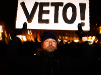 A man holds 'Veto' banner while demonstrating during 'Stop Lex Czarnek' protest at the Main Square in Krakow, Poland on February 15, 2022. S...