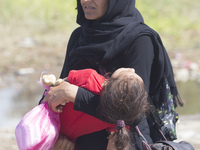A woman carries a child in Gewgelika, Macedonia, on September 11, 2015. Around 7,600 migrants entered Macedonia in just 12 hours overnight -...