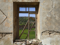 View of the fields through a broken window in a ruined house in the abandoned village of Souskiou. Cyprus, Sunday, February 20, 2022. This i...