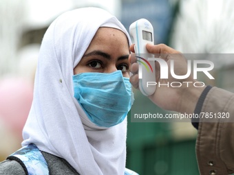 An employee checks the temperature of a student at the entrance of Baramulla public school in Baramulla Jammu and Kashmir India on 02 March...