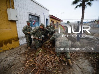 Chilean soldiers clean the debris left by the tsunami that ensued an 8.3 quake that left 12 people dead and five more missing, in Coquimbo,...