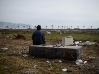 A man sits amid debris caused by the sea in Coquimbo on 19 September, some 445 km north of Santiago, during the eve's earthquake on Septembe...