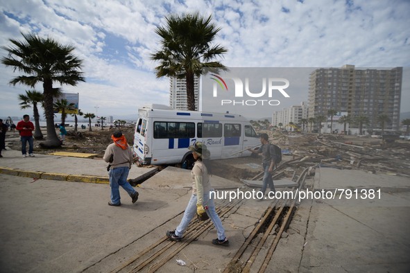 Residents walk between debris caused by the sea in the port of Coquimbo, some 445 km north of Santiago, during the eve's earthquake on Septe...