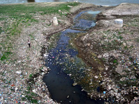 An indian man walks side of  heaps of waste in a waterway leading into a the River Ganges in Allahabad on September 21, 2015. The Ganges is...