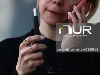 A woman smokes a cigarette using a tobacco heater
 in Krakow, Poland on March 28, 2022. (