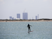 SpaceX's South Texas facility, called Starbase, is seen behind a kitesurfer. Starships SN16, SN15, SN22, and Booster 5 can be seen to the ri...