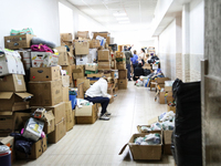 ODESA, UKRAINE - MARCH 30, 2022 - A woman browsing her phone is surrounded by cardboard boxes at the humanitarian centre for internally disp...