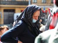 ODESA, UKRAINE - MARCH 30, 2022 - A woman in a black dotted headscarf and a face mask stands in a queue outside the humanitarian centre for...