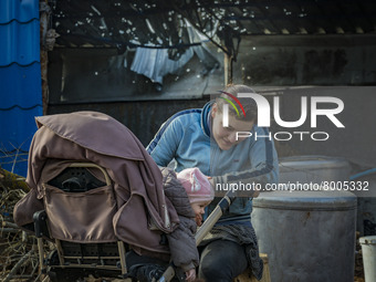 A mother cares her child near a shelled roof of a house in Mala Rohan, Kharkov. (