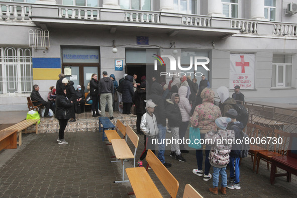 Ukrainian refugees who fled the war wait for receiving assistance at the entrance at the city humanitarian volunteer center for helping refu...