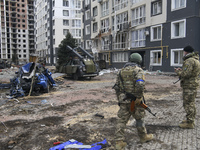 Ukrainian servicemen stands near Destroyed civil vehicles  near a damaged residential building in the recaptured by the Ukrainian army Bucha...