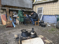 Local residents preparing a meal on fire near Residential building Destroyed by Russian army in the recaptured by the Ukrainian army Borodya...