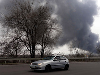 ODESA, UKRAINE - APRIL 3, 2022 - A car moves along a highway as a plume of smoke from the fire on the territory of an oil refinery and an oi...