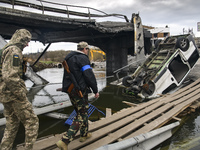 Ukrainian servicemen cross the Irpin river near a destroyed bridge outside the recaptured city of Irpin, Ukraine, 06 April 2022 (