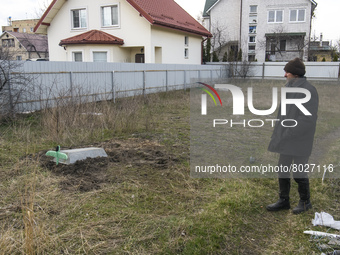 A local resident stands near the grave of a local citizen near her home in the recaptured by the Ukrainian army Hostomel city in Kyiv area,...