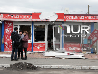 KYIV REGION, UKRAINE - APRIL 06, 2022 - People stand outside a kiosk damaged by the russian army shelling in Borodyanka, Kyiv Region, north-...