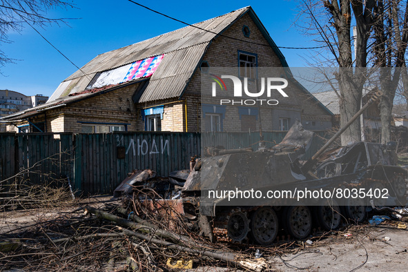 BUCHA, UKRAINE - APRIL 7, 2022 - A destroyed military vehicle is seen near a fence marked with the word 'People' after the liberation of the...