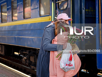 UZHHORORD, UKRAINE - APRIL 08, 2022 - A man with a bouquet of flowers hugs a woman as he meets her at the railway station of Uzhhorod, weste...