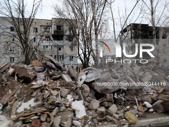 KYIV REGION, UKRAINE - APRIL 07, 2022 - Residential buildings damaged in the result of the russian military invasion are seen bihind a pile...