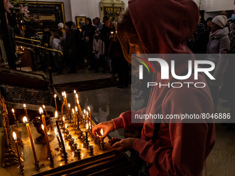 A woman lights candles during a Holy Mass in an orthodox church of the Dormition of the Virgin Mary in Krakow, Poland as 2,5 million people...