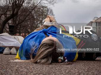 A protester lies on the ground for a reenactment of the murder of 163 people in Bucha during a rally at the White House for Ukraine.  Hundre...