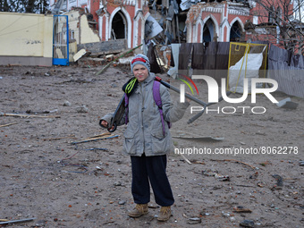 CHERNIHIV, UKRAINE - APRIL 11, 2022 - A boy with a kick scooter stands on a street covered by debris after the liberation of the city from R...