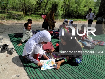 Students study at a Government school in a ground due to unavailability of school building on the outskirts of Rafiabad Baramulla, Jammu and...