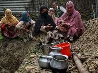 Women with pitcher pots wait for their turn to get water from a broken pipe in Baramulla, Jammu and Kashmir, India on 12 April 2022. People...