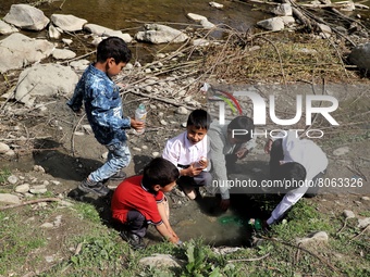 Students fill bottles with unhygienic water from a spring outside their school in Rafiabad, Baramulla, Jammu and Kashmir, India on 12 April...