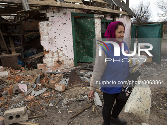 A woman collects the remains of things in a destroyed building, after artillery shelling, in the village of Andriyivka, Kyiv region, on Apri...