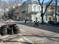 An Ukrainian citizen is seen passing in front of barricades made of tires, iron structures and cement blocks, in the streets of the center i...
