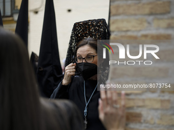 A penitent dressed in black from the Maria Santisima de la Concepcion Brotherhood puts a face mask during the Maundy Thursday in Granada, Sp...