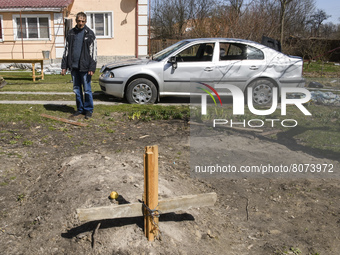 The local resident Serhiy shows the graves of his neighbor who was killed during the aviation shelling of the Russian army, at a yard of the...