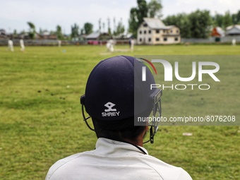 A Player wearing a Shrey Helmet looks on as kashmiri boys play cricket in Sopore during holy month of ramadan in Baramulla, Jammu and Kashmi...