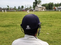 A Player wearing a Shrey Helmet looks on as kashmiri boys play cricket in Sopore during holy month of ramadan in Baramulla, Jammu and Kashmi...