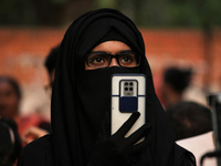 A woman wearing Hijab films a speaker during a demonstration against rise in hate crimes and anti-Muslim violence in New Delhi, India on Apr...