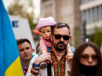 A young girl gets a ride on her father's shoulders as they march to the residence of the Russian ambassador during a protest against the war...