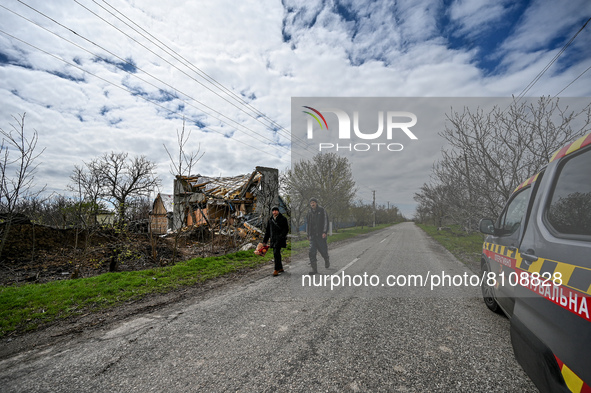 VESELIANKA, UKRAINE - APRIL 20, 2022 - People walk along a road past a building destroyed by Russian troops in Veselianka, Zaporizhzhia Regi...
